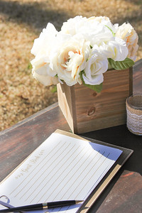 brown wood box with white roses at a wedding guest signing table