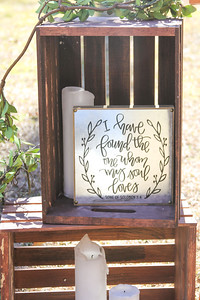Wood crates with white pillar candles and a Bible verse sign for wedding decor