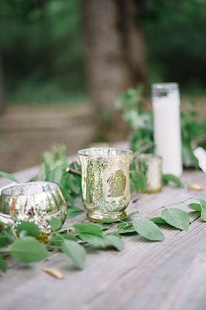 rustic wood table with gold mercury glass candle holders and greenery