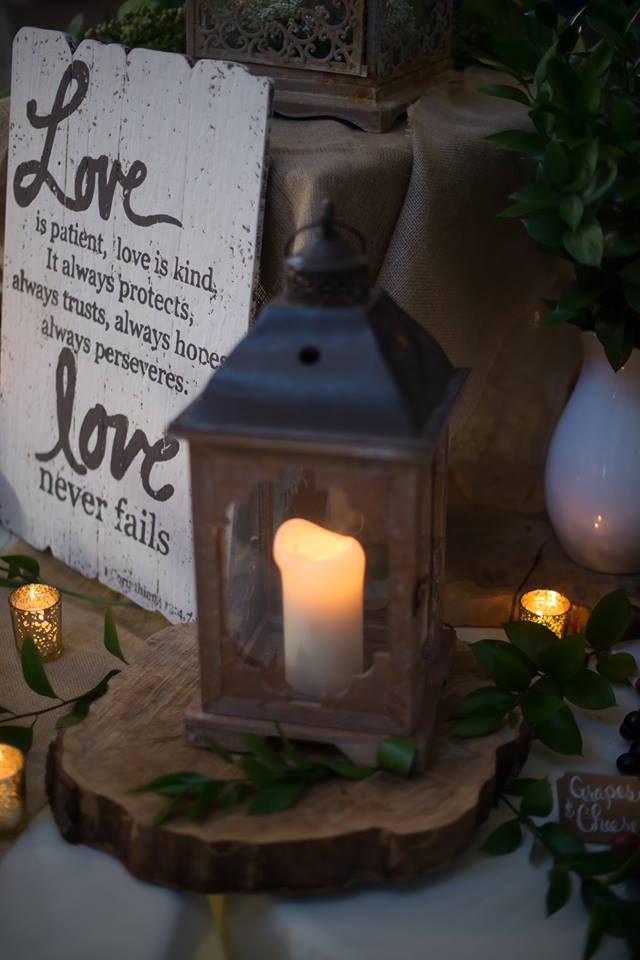 rustic lantern and candles on wood slice with a Bible verse sign, "love never fails" at a wedding reception