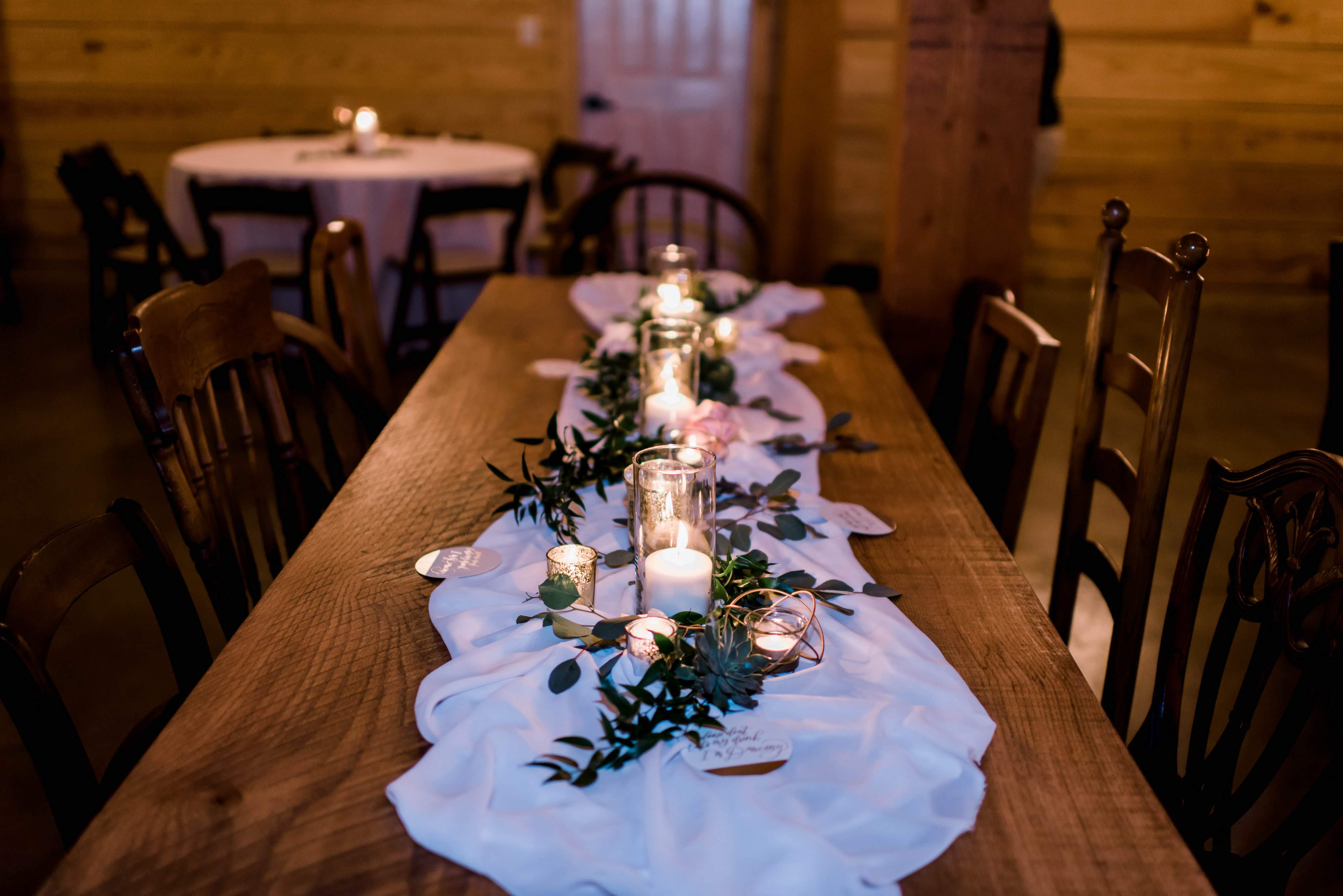 wedding reception table with candles and greenery