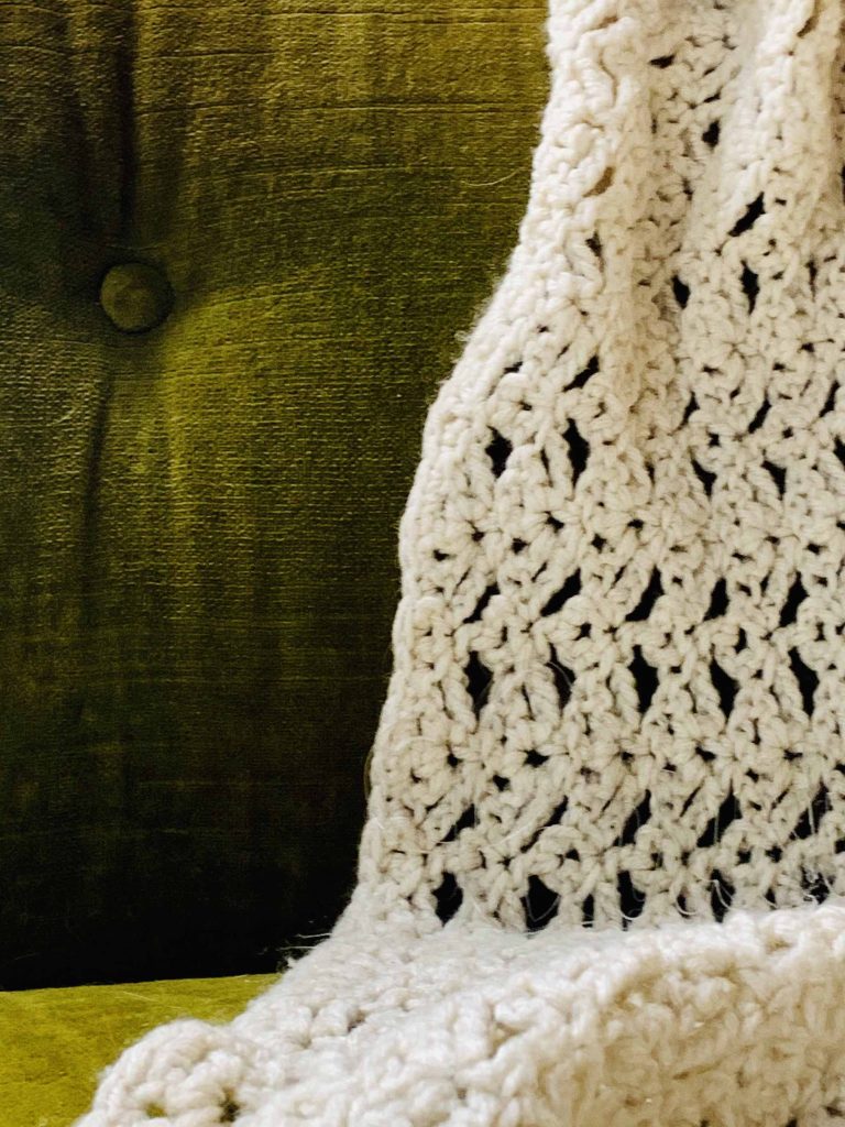 green couch with crochet blanket and Christ